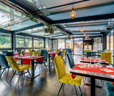Salle de restaurant avec tables et chaises sous verrière du Camping Domaine Les Oréades – Maeva Sélection