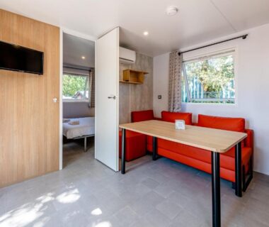 Intérieur du mobil-home avec banquette et table au Camping Domaine Les Oréades Maeva Sélection