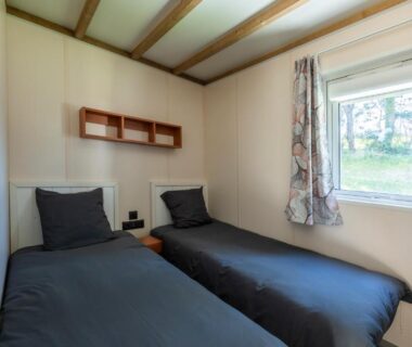 Chambre avec deux lits simples et fenêtre dans le mobil home du Camping Domaine Saâne et Mer