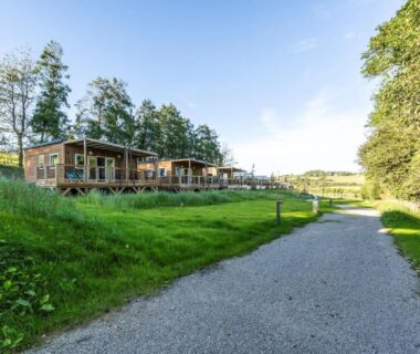 Allée bordée de chalets en bois au Camping Domaine Saâne et Mer