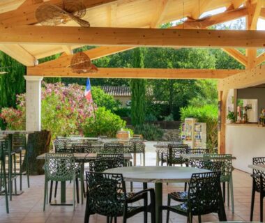 Terrasse couverte avec tables et chaises au Camping Domaine Villa Verde