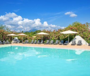 Piscine extérieure entourée de transats et parasols au Camping Domaine d'Anghione