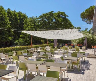 Terrasse extérieure avec tables et chaises sous voile d'ombrage au Camping Domaine d'Anghione