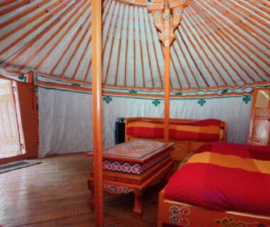Intérieur de yourte avec lits et table dans le camping Domaine de Mepillat