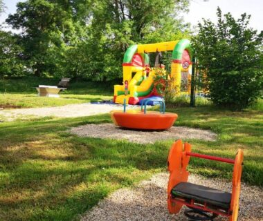 Aire de jeux sur pelouse avec château gonflable et jeu à ressort au Camping Domaine de Mepillat