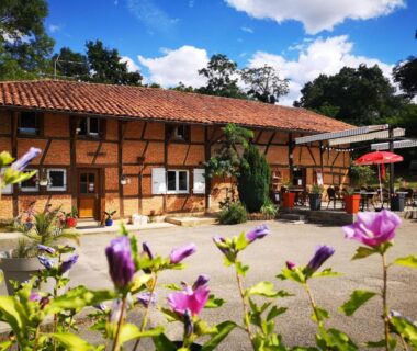 Cour fleurie avec terrasse et bâtisse à colombages au Camping Domaine de Mepillat