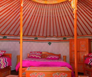 Intérieur de yourte avec lits colorés et mobilier peint au Camping Domaine de Mepillat