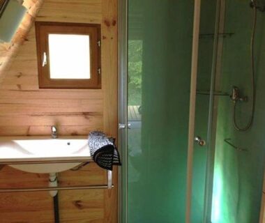 Salle de bain en bois avec douche et lavabo au Camping Domaine de Mepillat