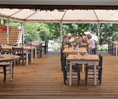 Terrasse couverte avec tables et chaises en bois sur deck au Camping Domaine de la Brèche