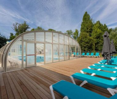 Piscine couverte et transats sur terrasse au Camping Domaine de la Brèche