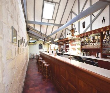 Bar intérieur avec comptoir en bois et tabourets au Camping Domaine de la Brèche
