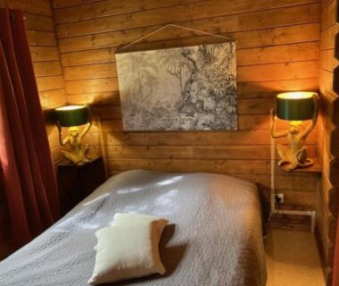 Chambre en bois avec lit et lampes au Camping Domaine de la GAUTIERE