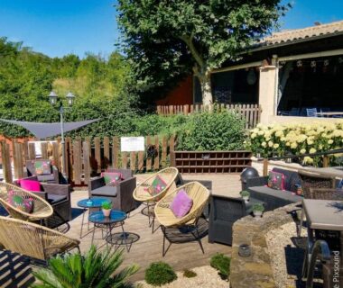 Terrasse extérieure avec fauteuils en rotin et tables au Camping Domaine de la GAUTIERE
