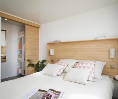 Chambre de mobile-home avec lits doubles et tête de lit en bois au Camping Domaine de la Ville Huchet