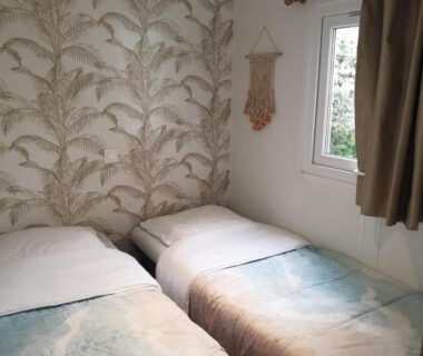 Chambre avec deux lits et papier peint feuillage au Camping Domaine des Iscles