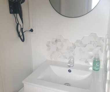 Salle de bain avec lavabo miroir et sèche-cheveux au Camping Domaine des Iscles