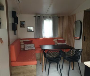 Intérieur séjour avec banquette orange et table à manger du Camping Domaine des Iscles