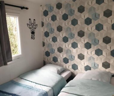 Chambre avec deux lits simples et papier peint hexagonal au Camping Domaine des Iscles