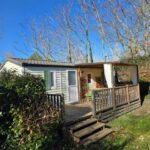 Terrasse en bois et mobil-home au milieu des arbres au Camping Domaine des Iscles