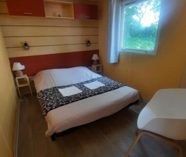 Chambre avec lit double et fenêtre dans le Camping Domaine des iscles