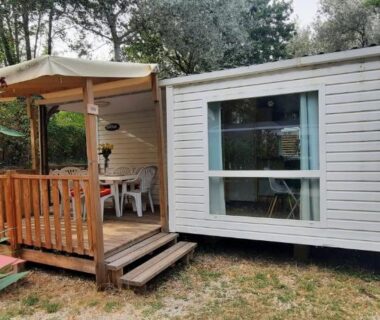 Terrasse en bois avec mobil-home et salon extérieur au Camping Domaine des iscles