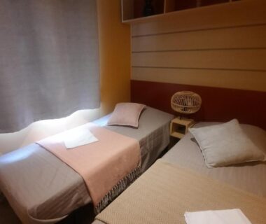 Chambre avec deux lits et fenêtre au Camping Domaine des iscles