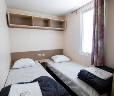 Chambre avec deux lits et serviettes pliées dans le Camping Domaine du Cros d'Auzon Maeva