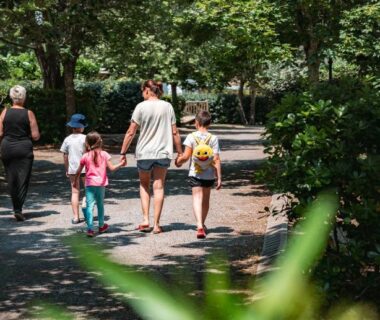 Allée ombragée avec famille marchant au Camping Domaine du Cros d'Auzon - Maeva
