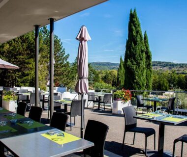 Terrasse extérieure avec tables et parasols du Camping Domaine du Cros d'Auzon - Maeva