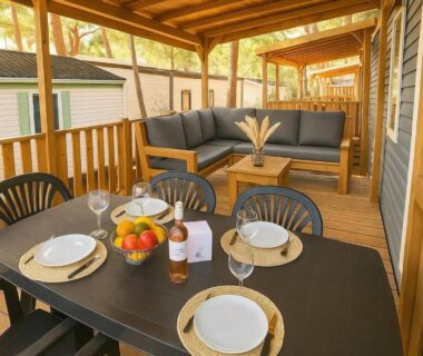 Terrasse couverte avec table dressée et salon extérieur du mobile-home Camping Domaine la Yole