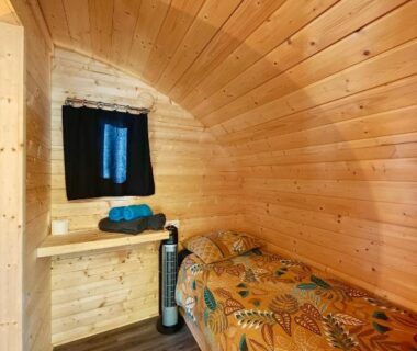 Intérieur de cabine en bois avec lit au Camping Du Paquier Fané