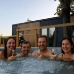 Jacuzzi extérieur avec quatre adultes et verres de vin au Camping Du Perche Bellemois