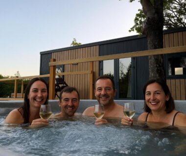Jacuzzi extérieur avec quatre adultes et verres de vin au Camping Du Perche Bellemois