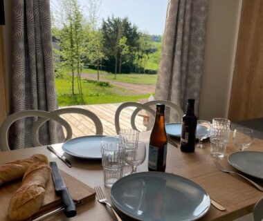 Salle à manger avec table dressée près de la baie vitrée du Camping Du Perche Bellemois