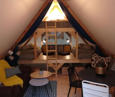 Intérieur de tente avec lits superposés et coin salon au Camping Du Port De Plaisance