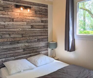 Chambre avec lit double et mur en bois au Camping Du Port De Plaisance