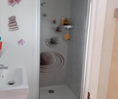 Salle d'eau avec cabine de douche et stickers décoratifs dans le Camping Ernest Renan