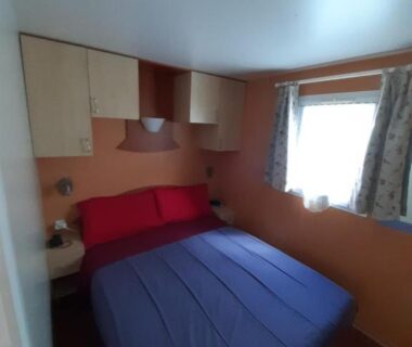 Chambre double avec lit rangements et fenêtre au Camping Ernest Renan