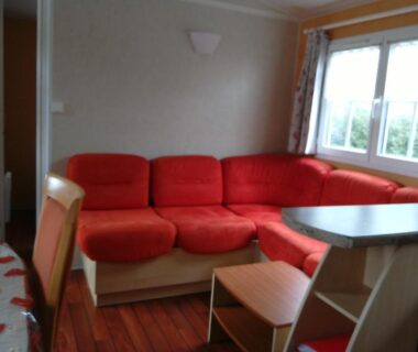 Salon avec banquette rouge et table dans l'hébergement du Camping Ernest Renan