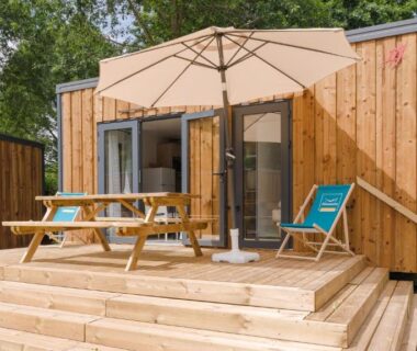 Terrasse en bois avec parasol et table de pique-nique au Camping Etennemare