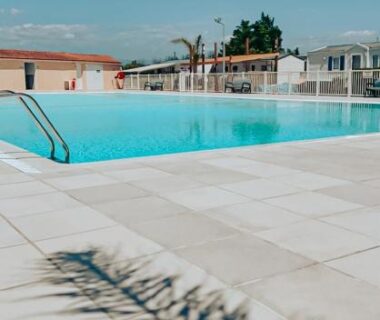 Bord de piscine avec ombre de palmier au Camping Europcamping