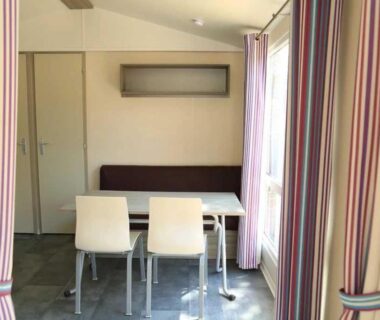 Coin repas intérieur avec table et deux chaises dans l'hébergement du Camping Figurotta