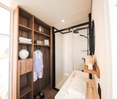 Salle de bain avec douche vitrée et étagères au Camping Golfo Di Sogno