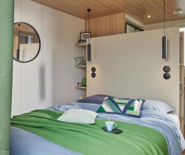 Chambre avec lit vert coussins miroir et suspensions au Camping Golfo Di Sogno