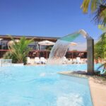 Piscine extérieure avec cascade d'eau, transats et parasols au Camping Haliotis