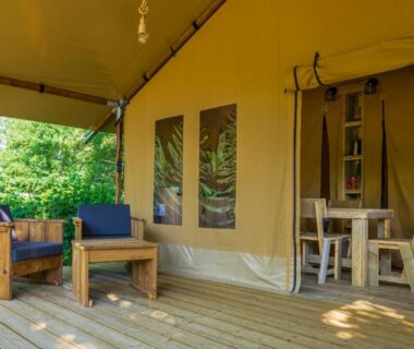 Terrasse en bois avec fauteuils et table devant tente safari au Camping Haliotis