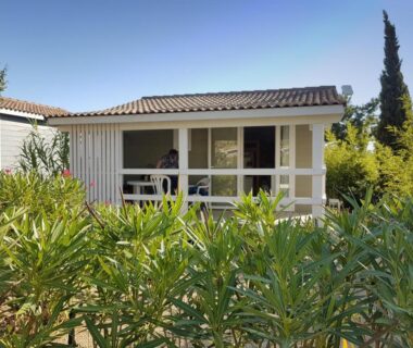 Véranda couverte entourée de buissons au Camping Hameau Des Cannisses