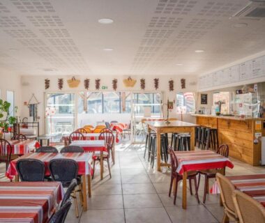 Salle de restaurant avec tables rayées et comptoir au Camping Harrobia