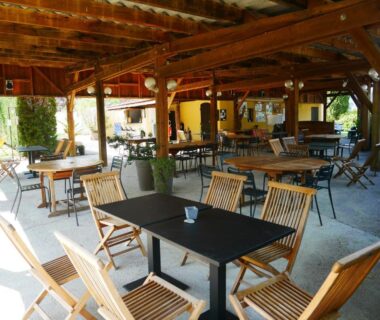 Terrasse couverte avec tables et chaises au Camping Hello Soleil