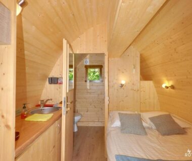 Intérieur de chalet en bois avec lit et kitchenette au Camping-Hotel de Plein Air Les 2 Bois